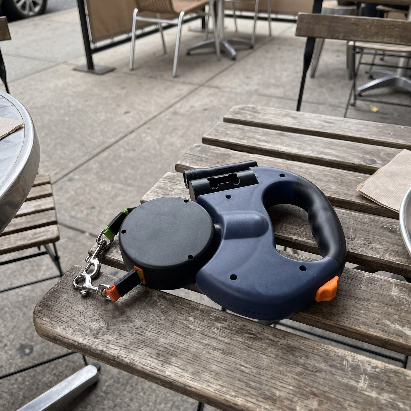 Phone photograph of leash resting on outdoor cafe bench after a walk, both clips